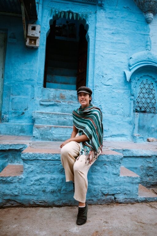 Haylea sitting in front of Blue Buildings in India