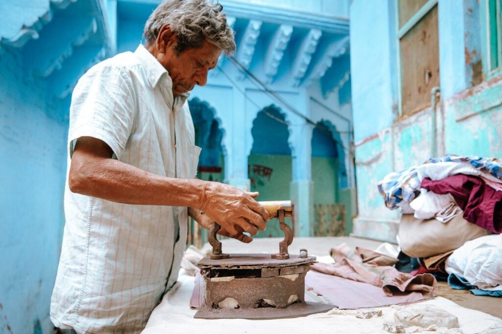 Man ironing in Chandpole of the Blue City, India