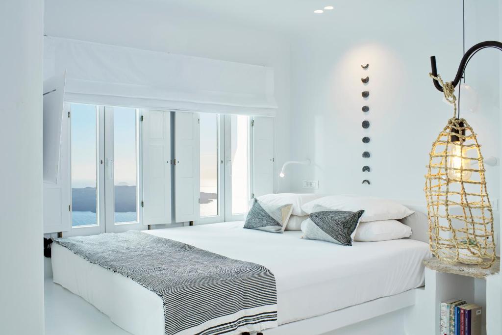 Bright white bedroom with sea views at Cosmopolitan Suites in Fira, Greece