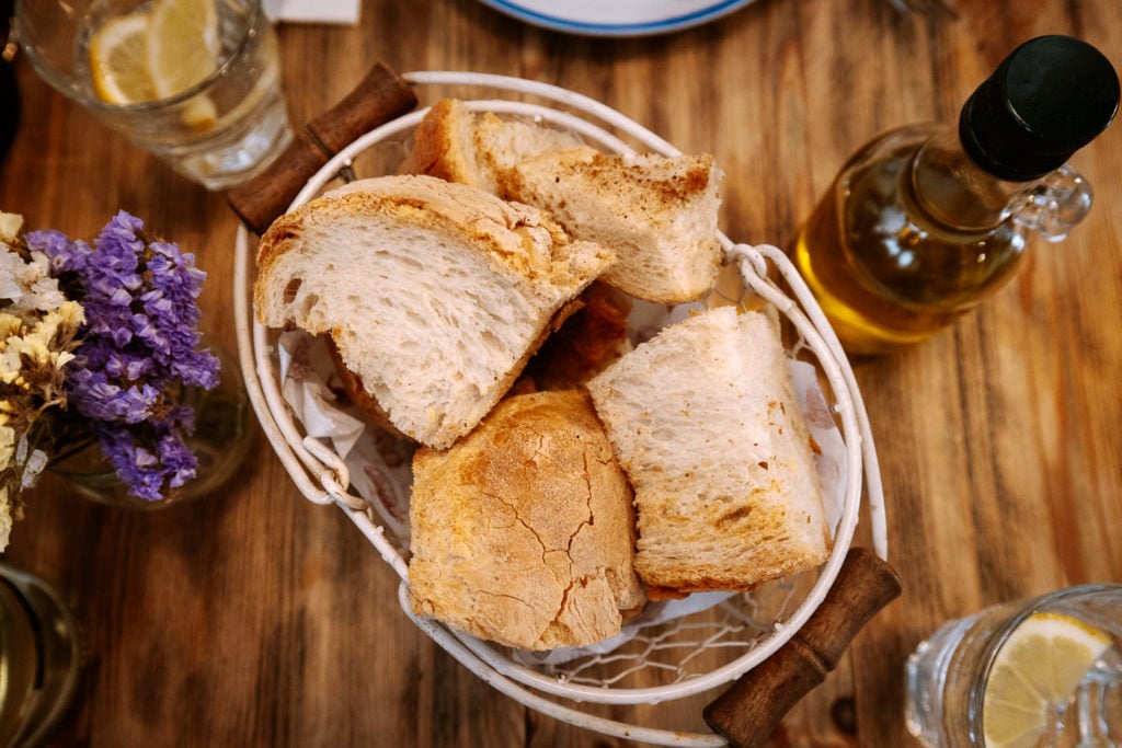 Fresh bread in a basket with olive oil and flowers