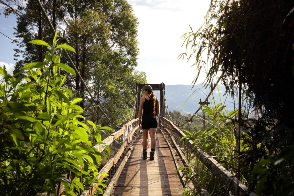 Girl hiking across a bridge in Colombia